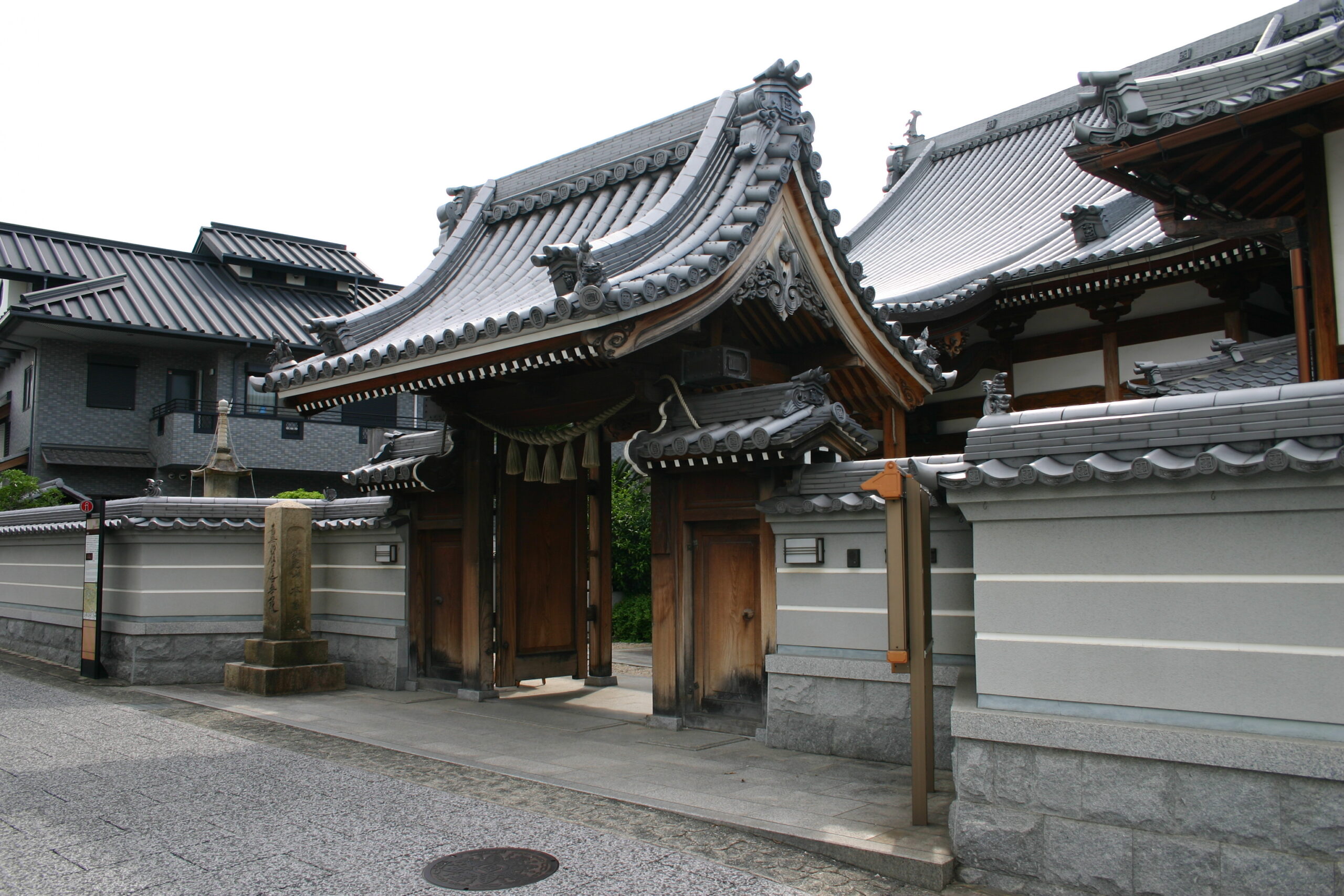 伝統的な瓦屋根が特徴的な本昌寺の山門と石碑