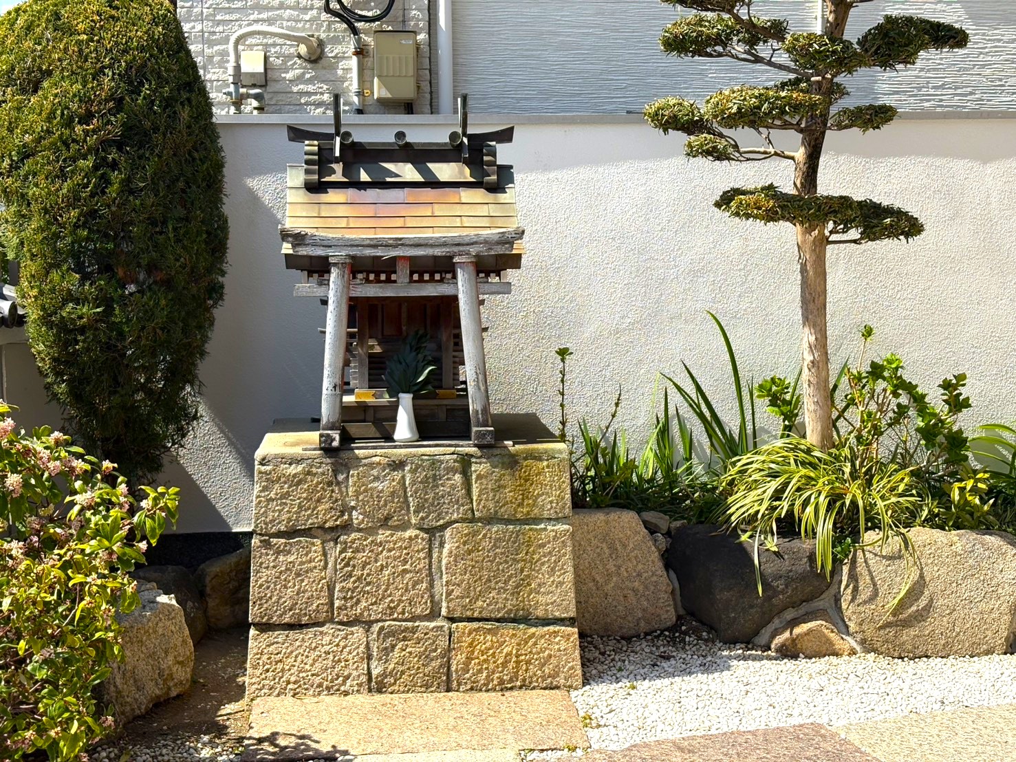 豊運寺の境内に祀られた石積みの台座に乗る小さな祠