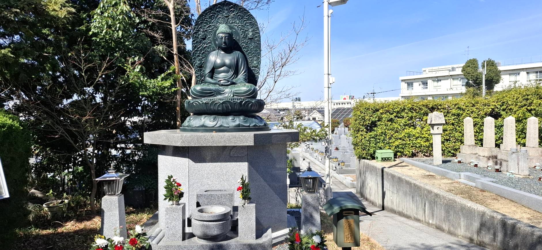 屋外の石台座に安置された、慈愛に満ちた表情の青銅製の釈迦如来像