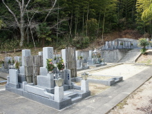 自然豊かな山裾に位置する、日当たりの良い明るい霊園の区画風景。