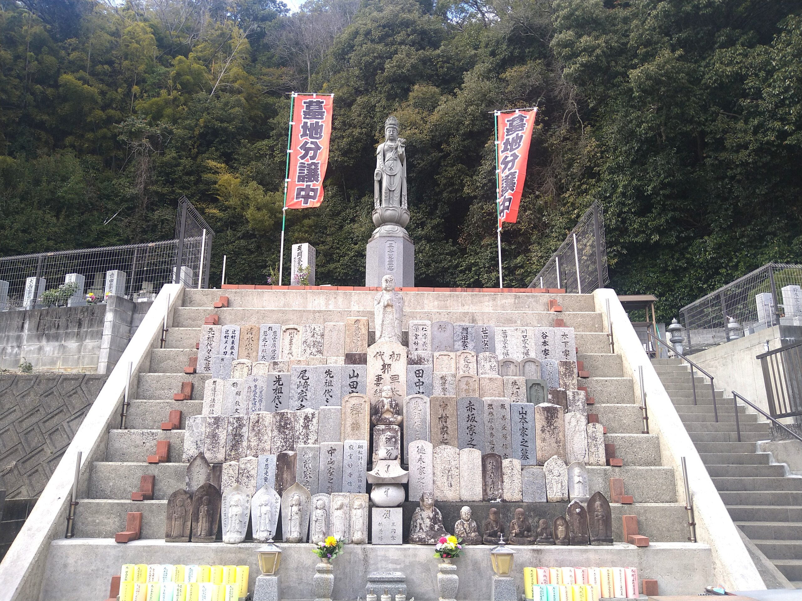 中央に立つ観音菩薩像と背後に並ぶ古い墓碑群
