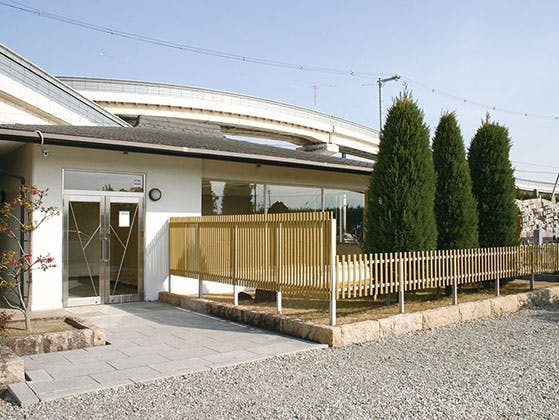 手入れされた植栽に囲まれた白い壁の霊園休憩所