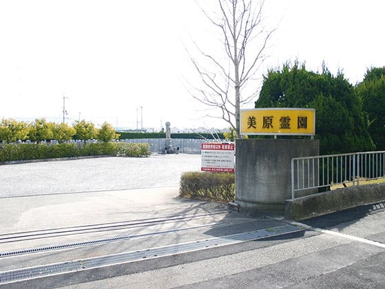 大きな駐車場と観音像が見える霊園の正面ゲート