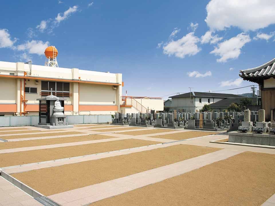 青空の下に広がる日当たりの良い平坦な寺院墓地