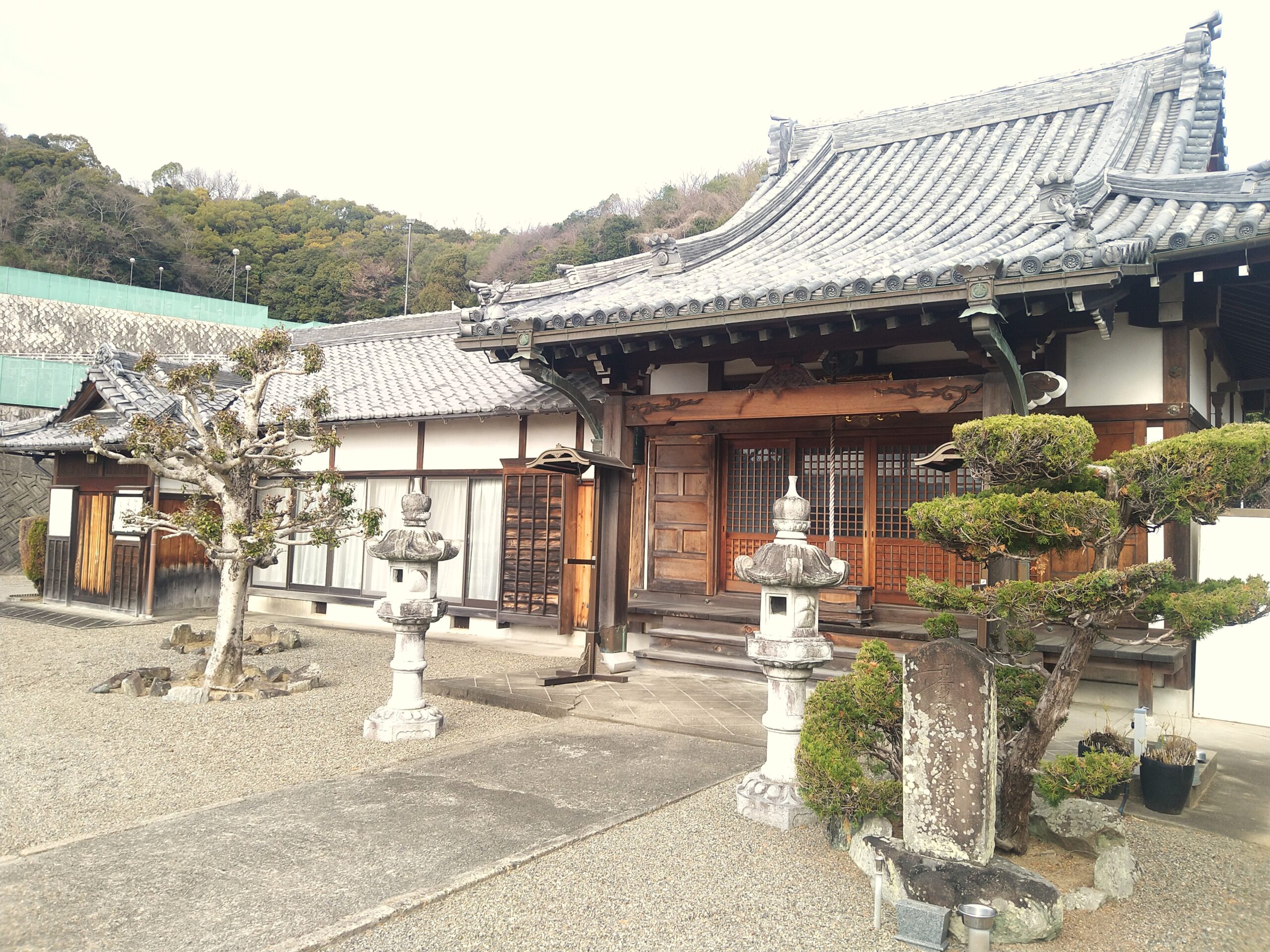 伝統的な日本建築の本堂と石灯籠がある寺院の境内