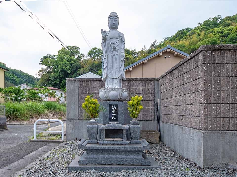 霊園を見守るように安置された石造りの仏像と供花