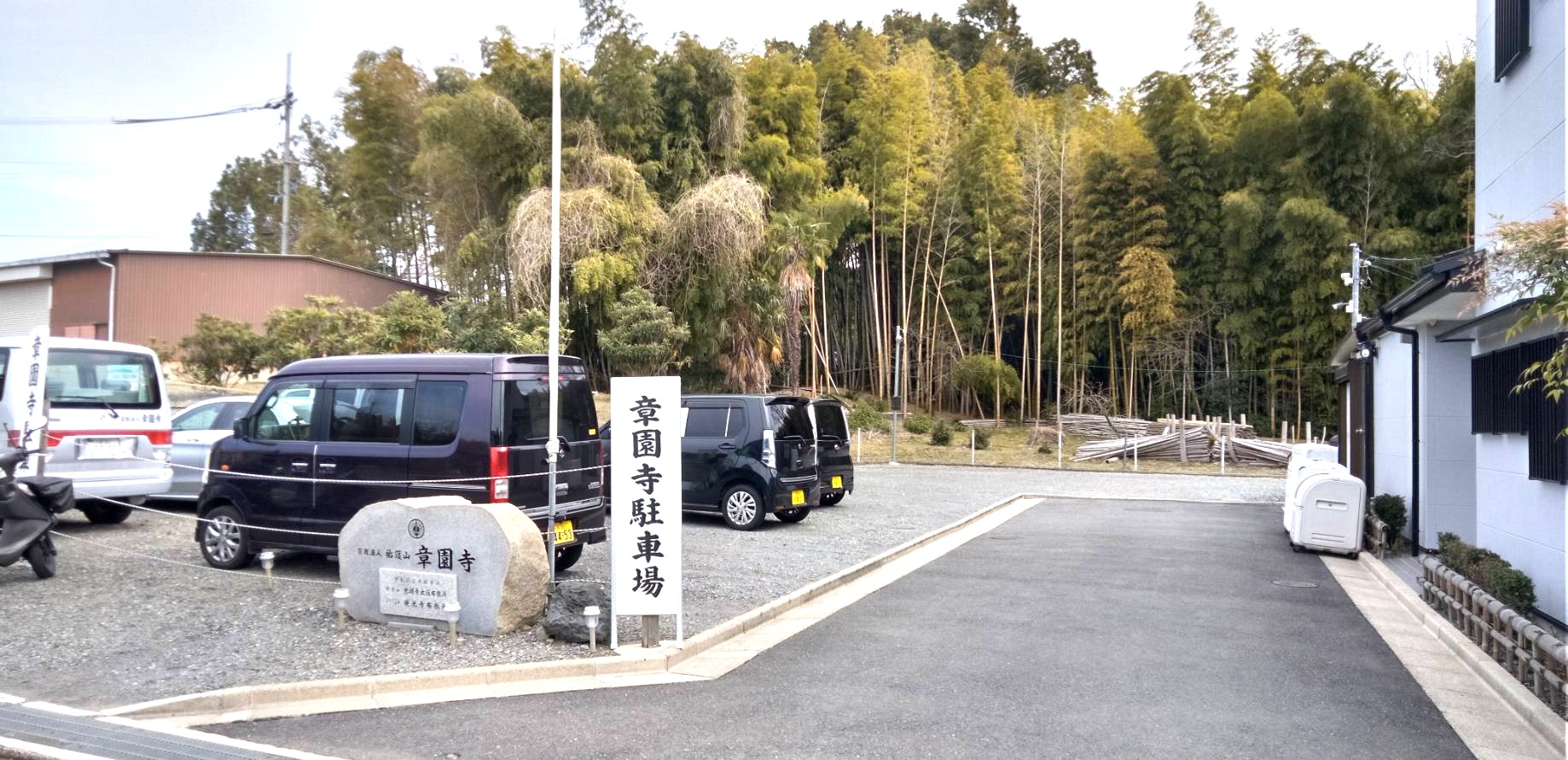 「章園寺駐車場」の看板と車が数台停まった砂利敷きの駐車スペース