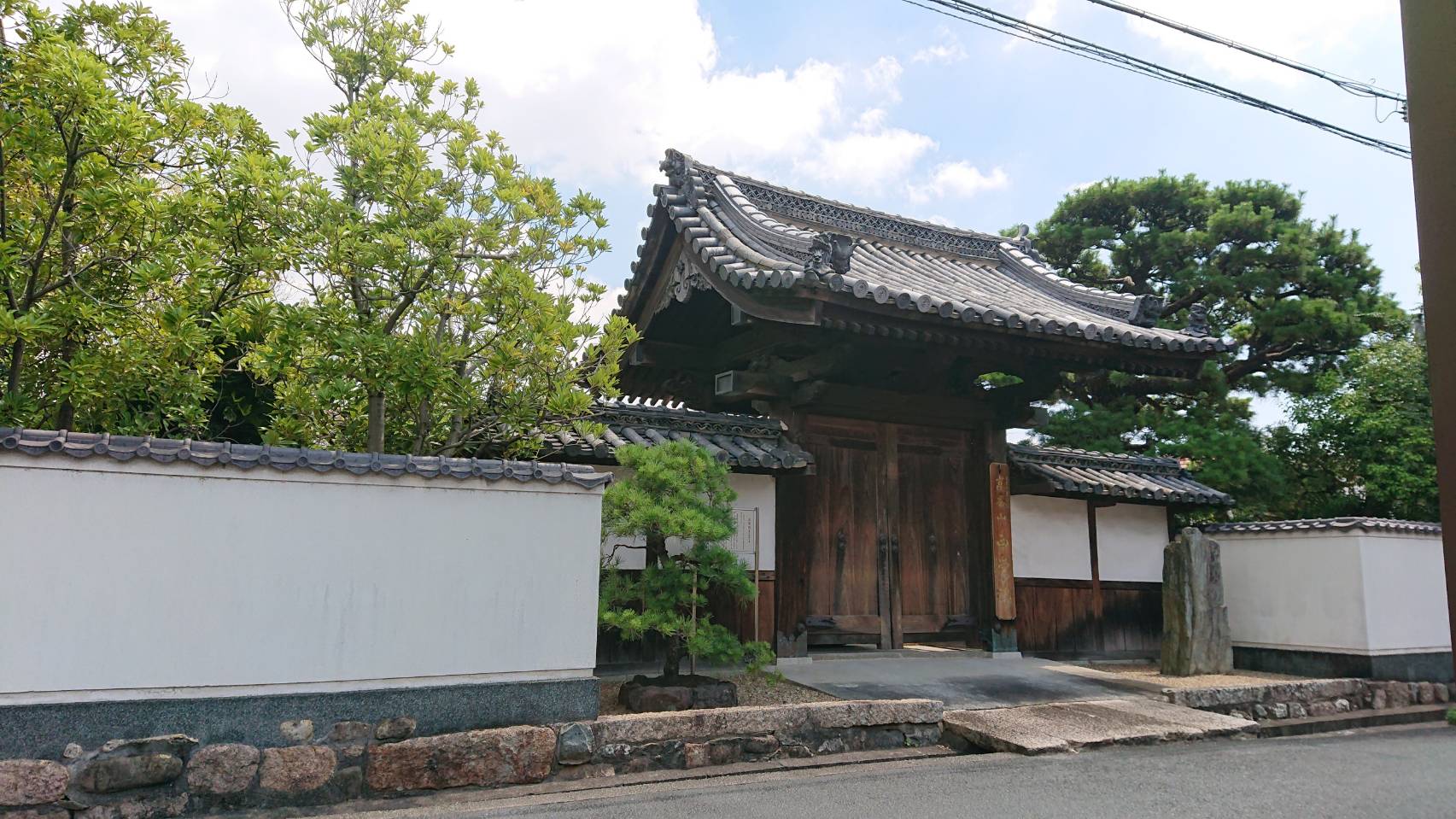 重厚な瓦屋根と木造の門構えがある日本の伝統的な寺院の入り口