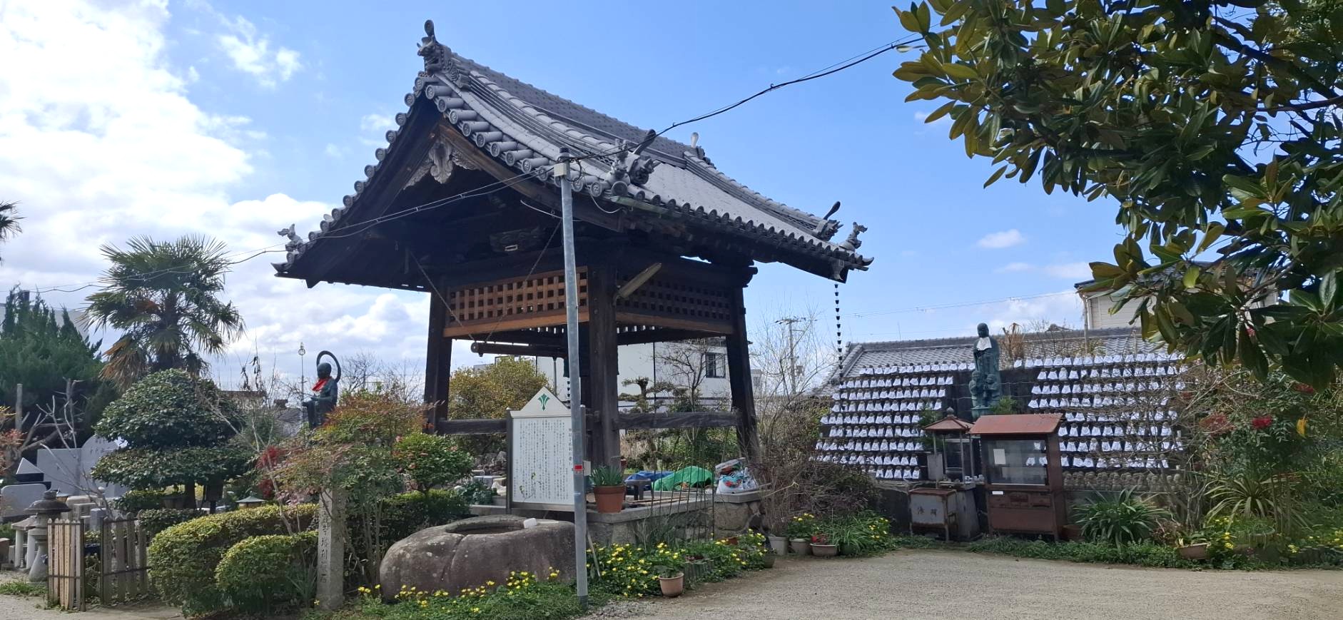 境内に建つ立派な鐘楼堂と多くの石仏が並ぶ風景