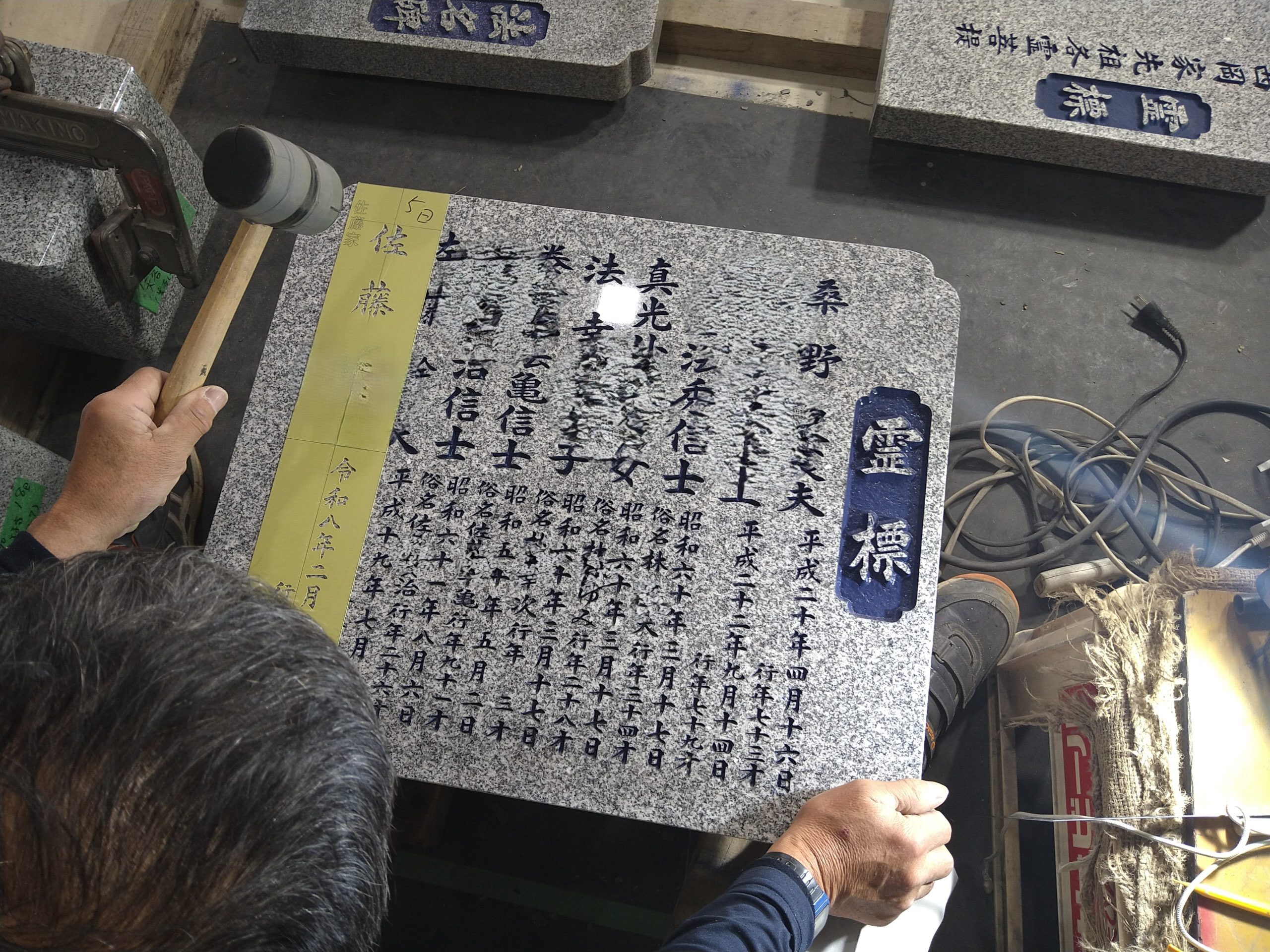 熟練の職人が墓石の表面に彫り込まれた文字の細部を調整する様子