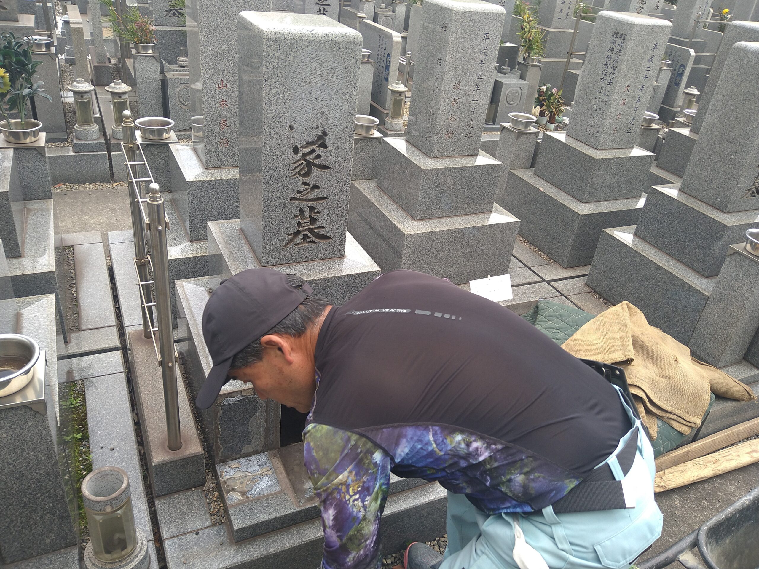 墓地の区画内で、しゃがんで作業を行うスタッフ